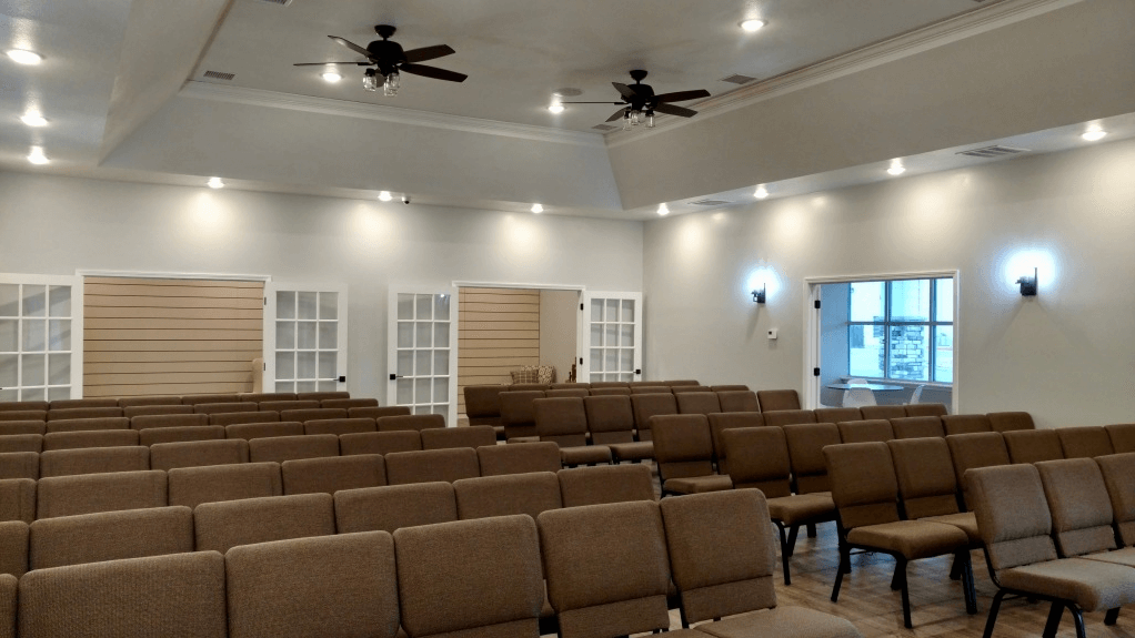 A large room with rows of chairs and a ceiling fan