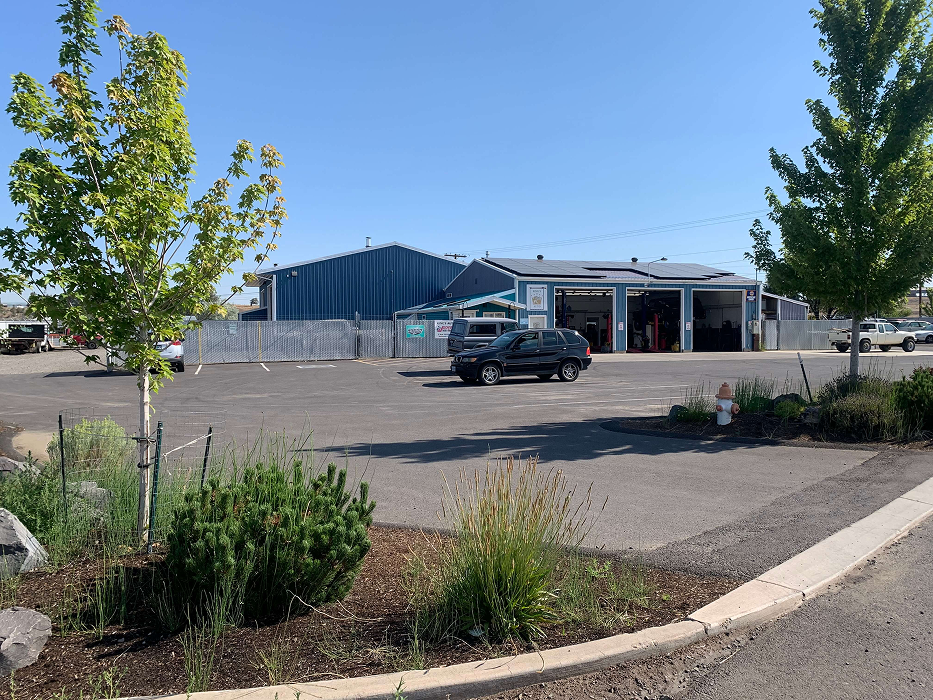 A black SUV in a parking lot, with buildings and trees in the background under a blue sky. | King's Auto LLC