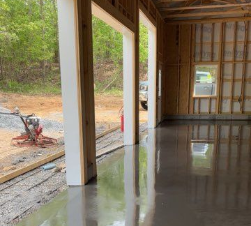 Interior of a new garage with a wet, gray concrete floor reflecting the surroundings; white trim and an outside view.