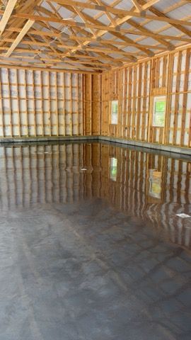 Interior of a new garage with a smooth, reflective gray concrete floor and exposed wooden beams.