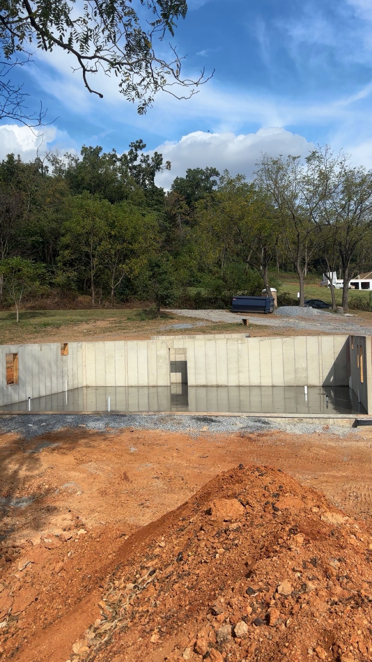 Foundation of a building under construction, with concrete walls and dirt.