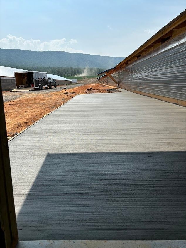 Newly poured concrete walkway next to a building under construction, with mountains in the background.