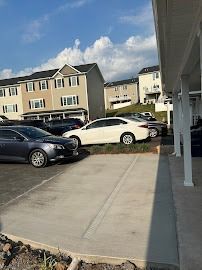 Parking lot with several cars parked in front of townhouses under a blue sky.