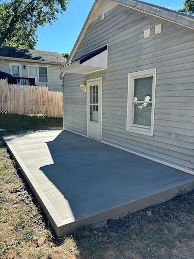 Gray house exterior with a newly poured gray concrete patio.