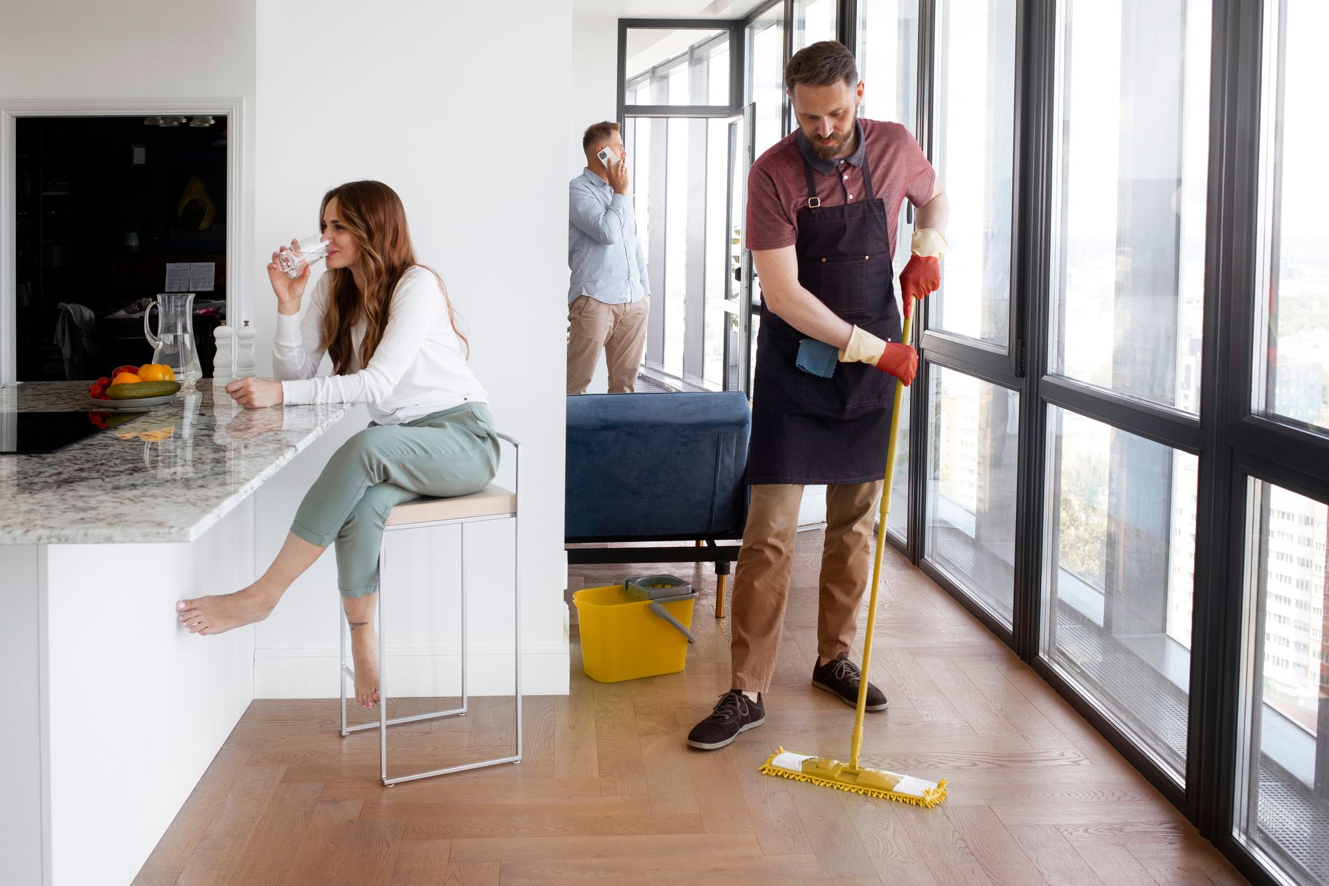 a man is mopping the floor while a woman sits at a bar drinking a glass of water