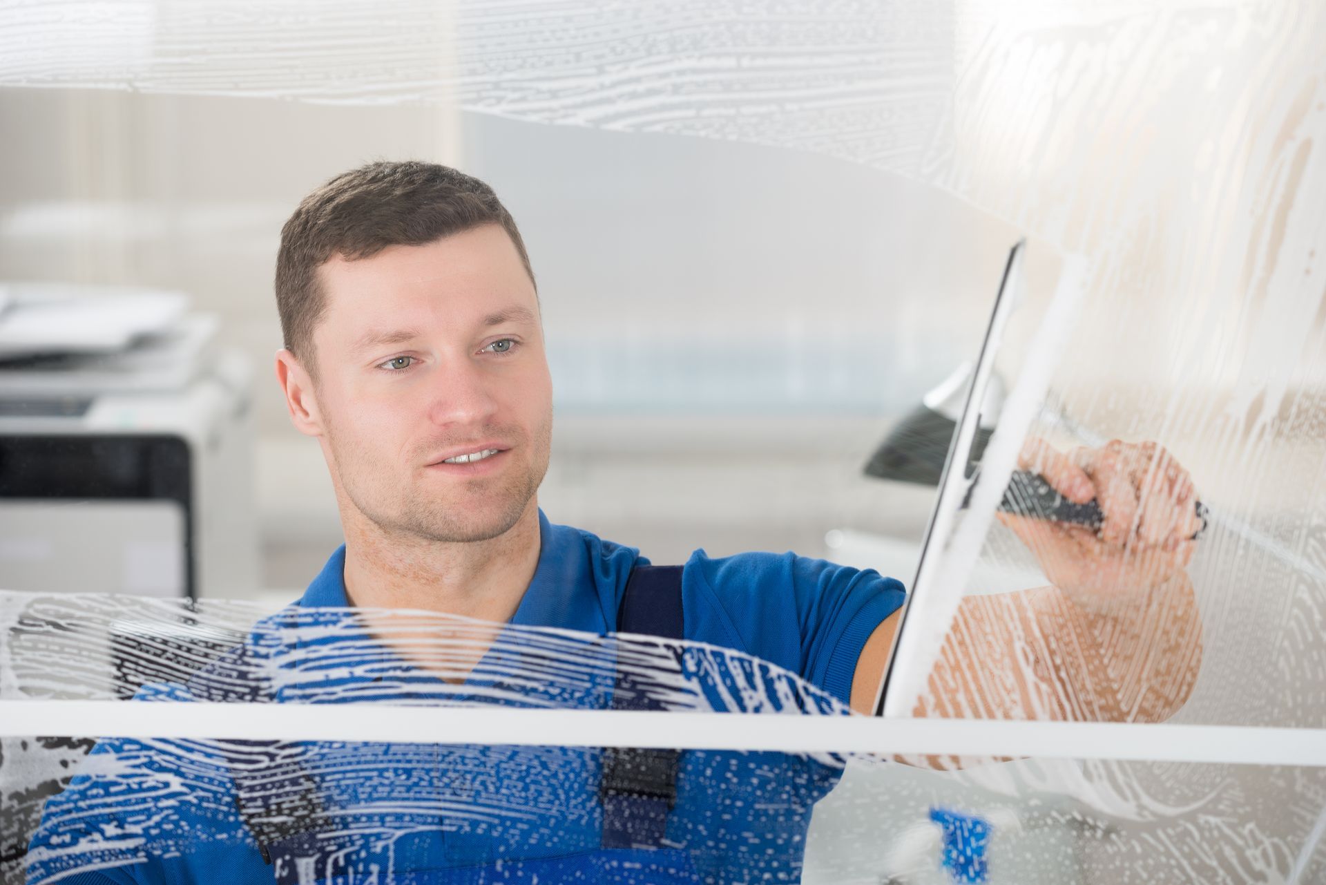 A man is cleaning a window with a squeegee.