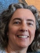 A woman with gray hair is smiling for the camera.