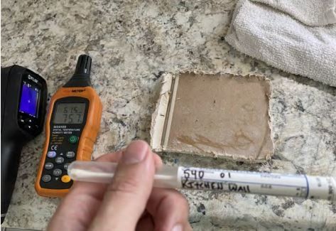 A person is holding a marker in front of a thermometer.