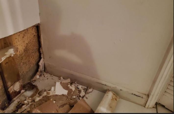 A room with a hole in the wall and a lot of cardboard on the floor.