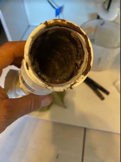 A person is holding a dirty pipe in their hand.