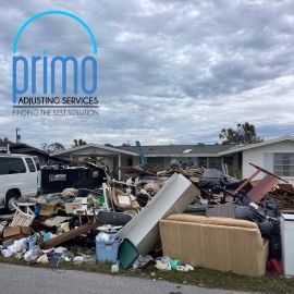 A pile of garbage in front of a primo adjusting services sign