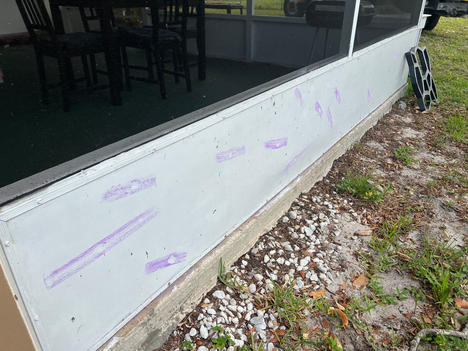 A screened in porch with a table and chairs in the background.