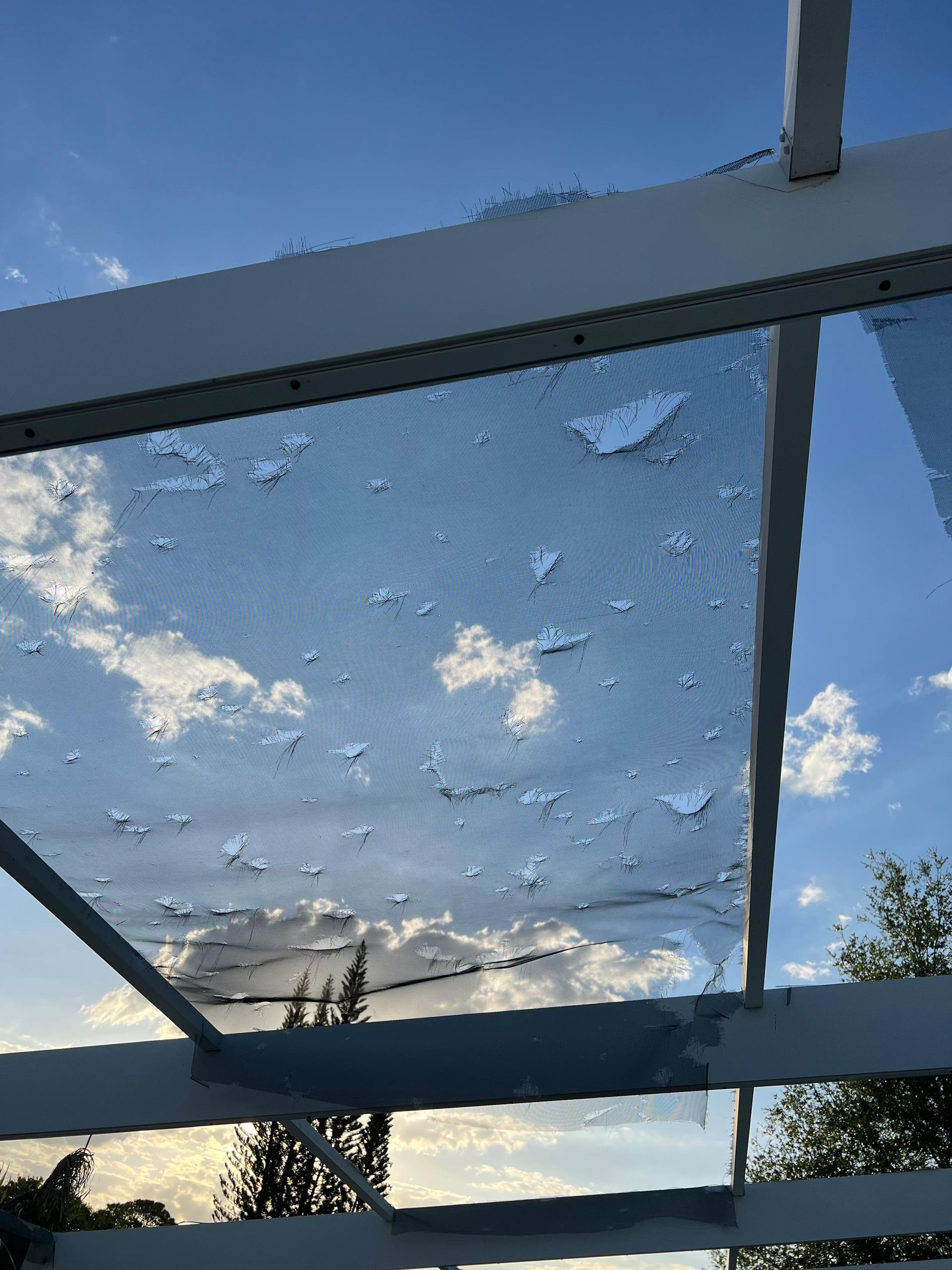 A broken glass roof with a blue sky behind it