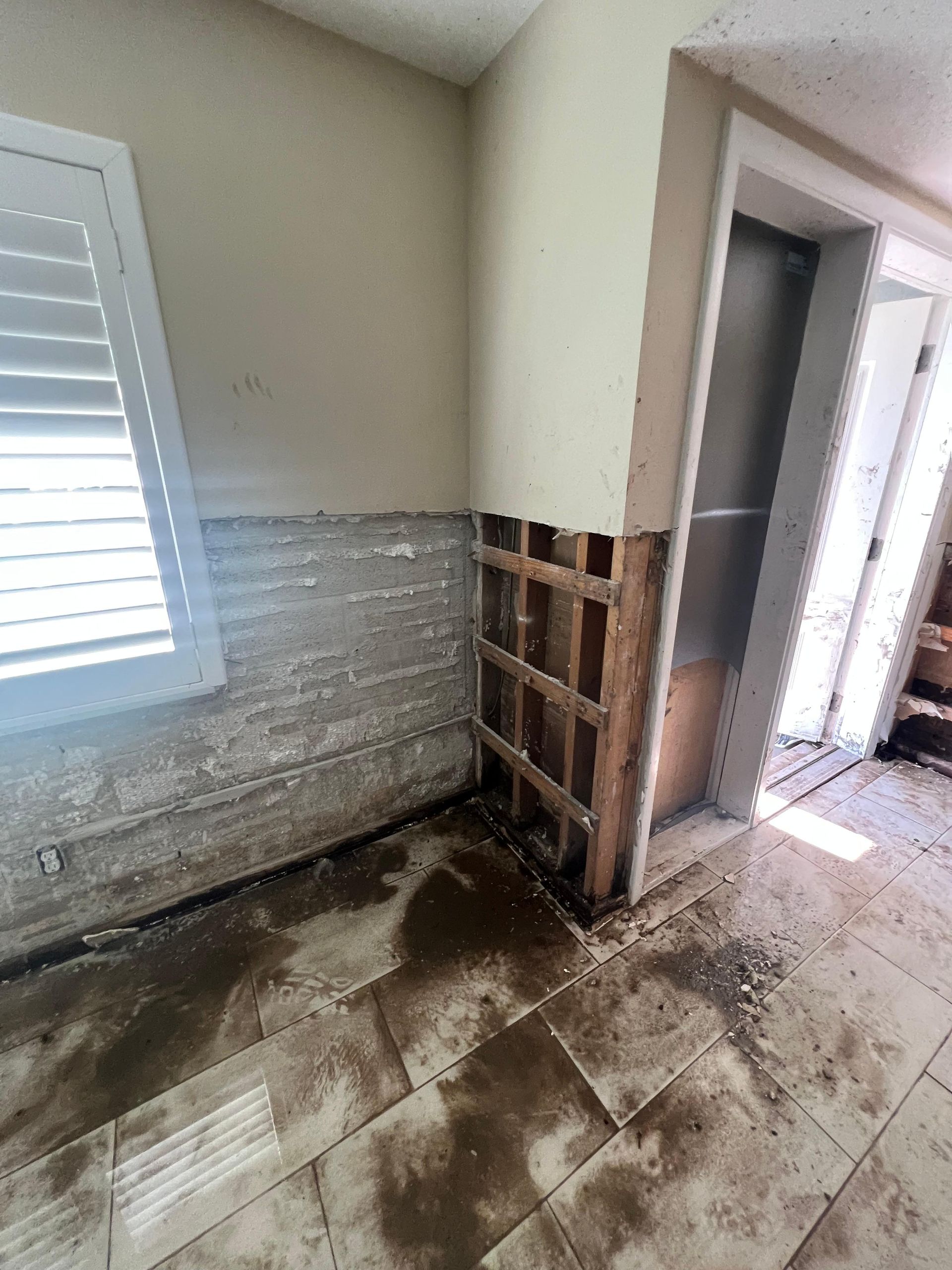 A room with a broken wall and a door.