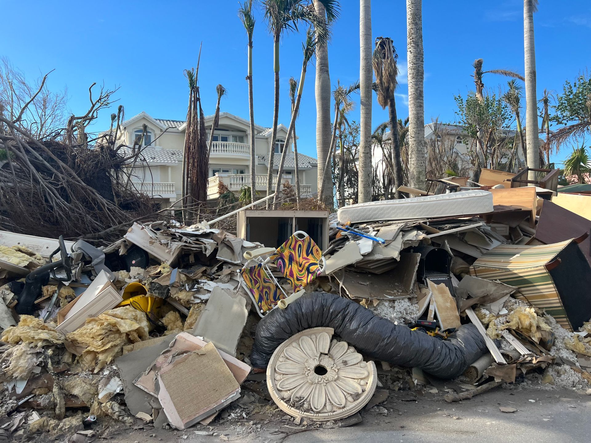 A pile of rubble is sitting on the side of the road in front of a house.