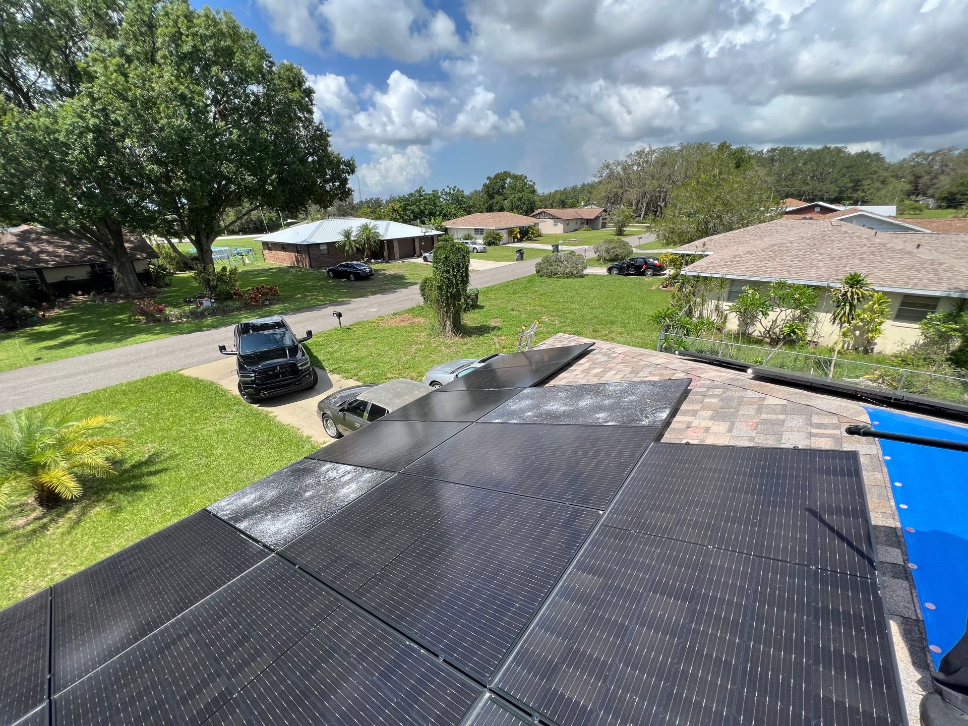 A person is cleaning a solar panel on the roof of a house.