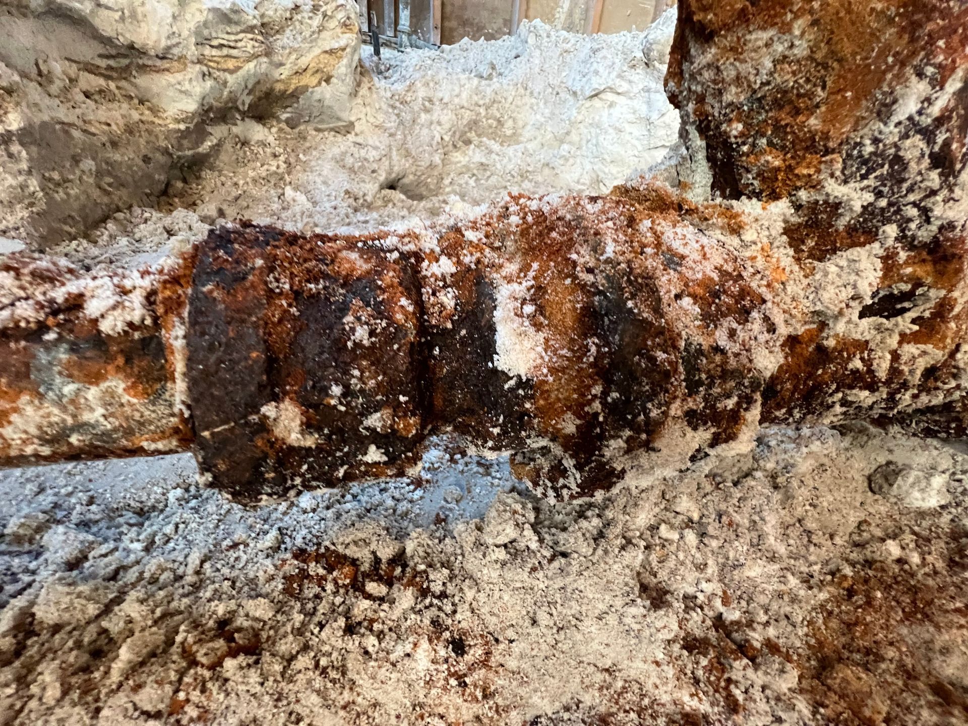 A close up of a rusty pipe covered in white powder.