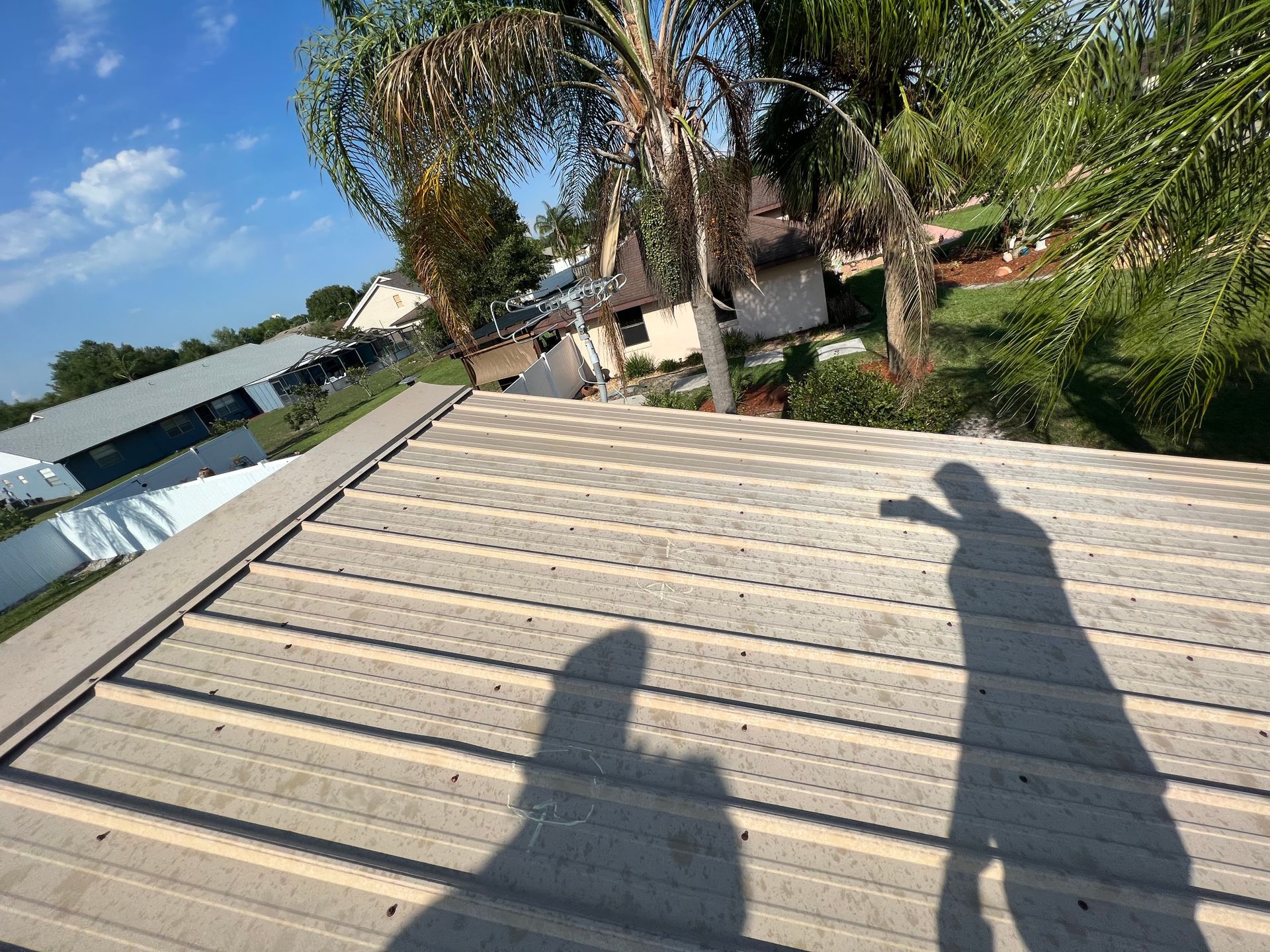 A shadow of a person is cast on the roof of a house.
