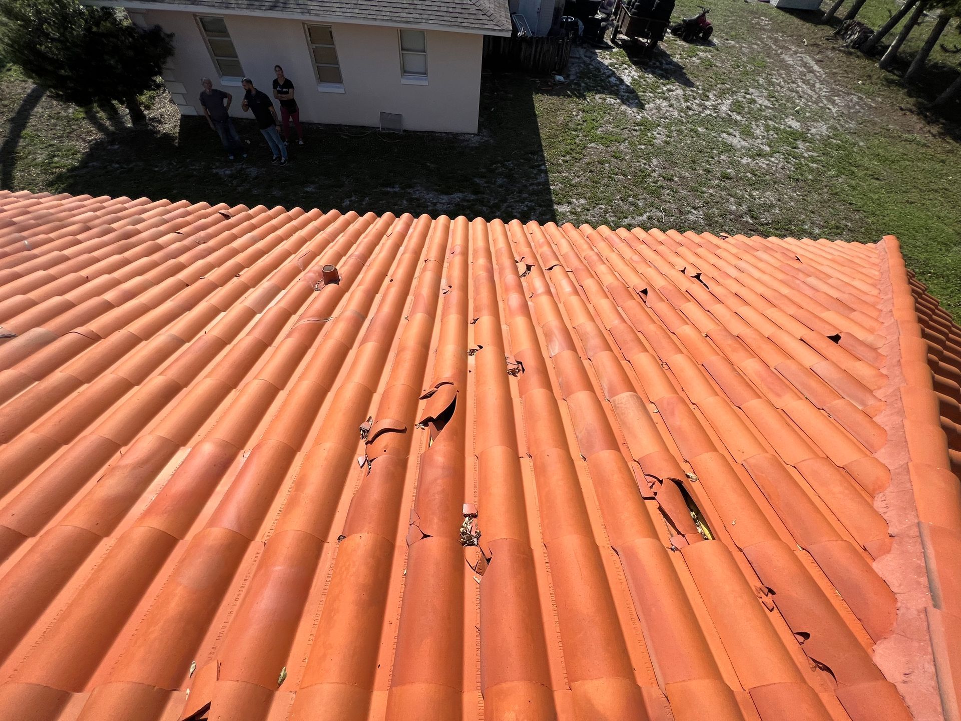 An aerial view of a tiled roof with a house in the background