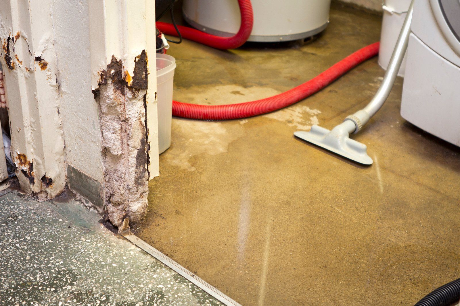 A vacuum cleaner is being used to clean a dirty floor in a basement.
