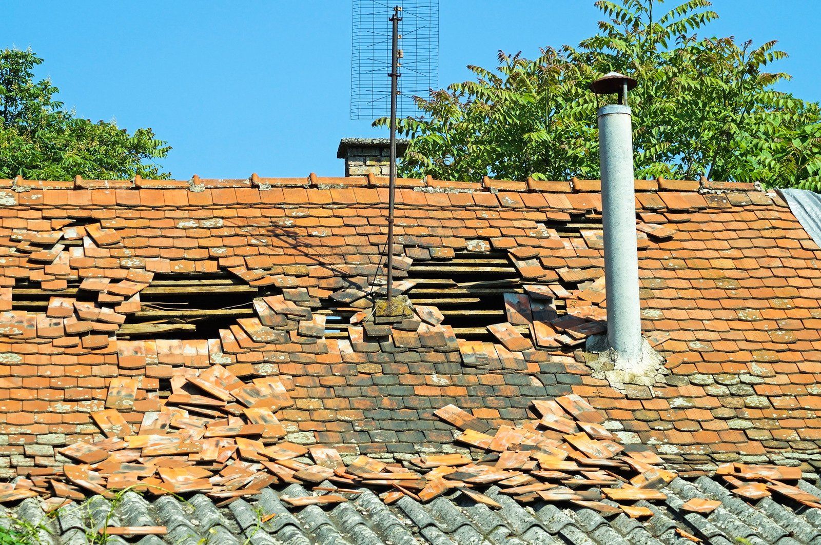 A roof with a chimney and antenna on it.