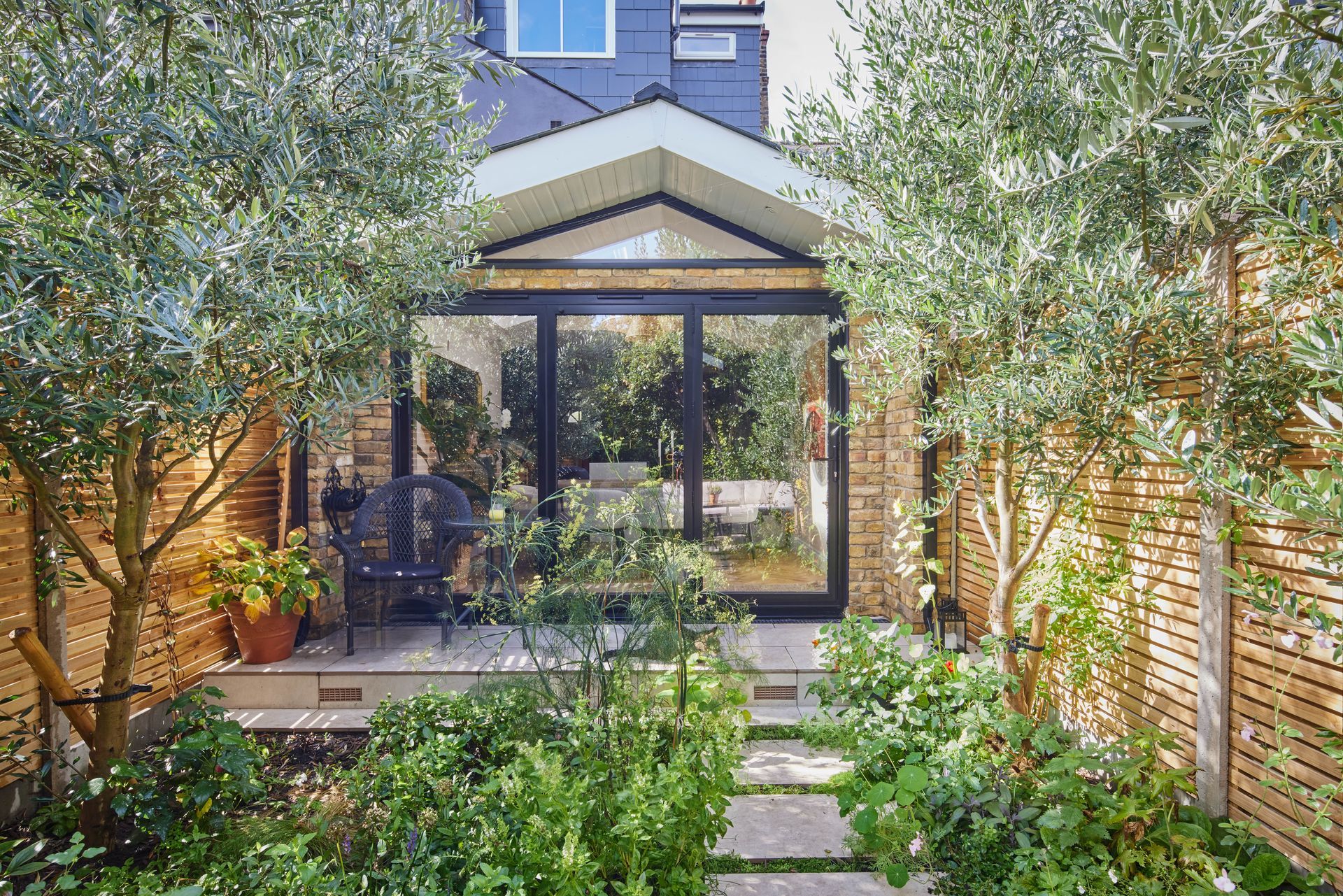 A house with a lot of windows and trees in the backyard.