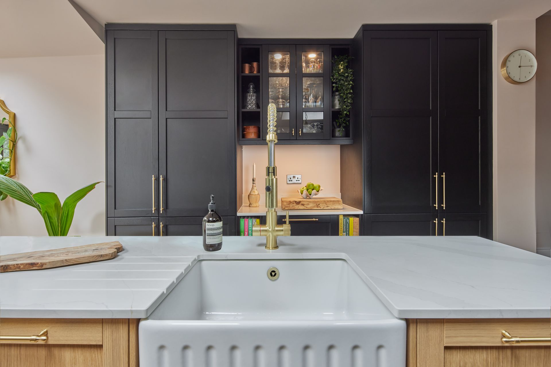 A kitchen with a sink and a clock on the wall.