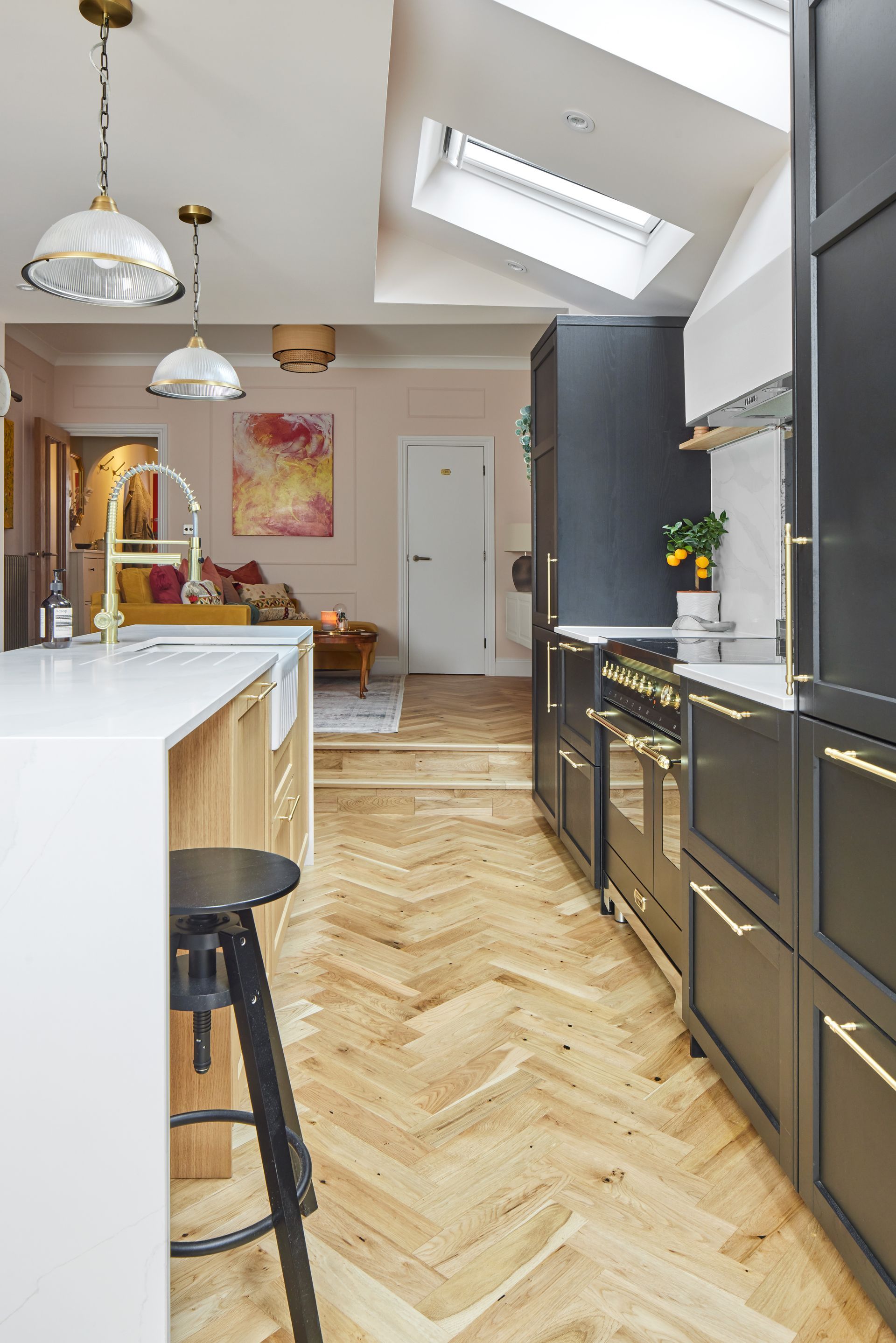 A kitchen with black cabinets and wooden floors and a skylight.