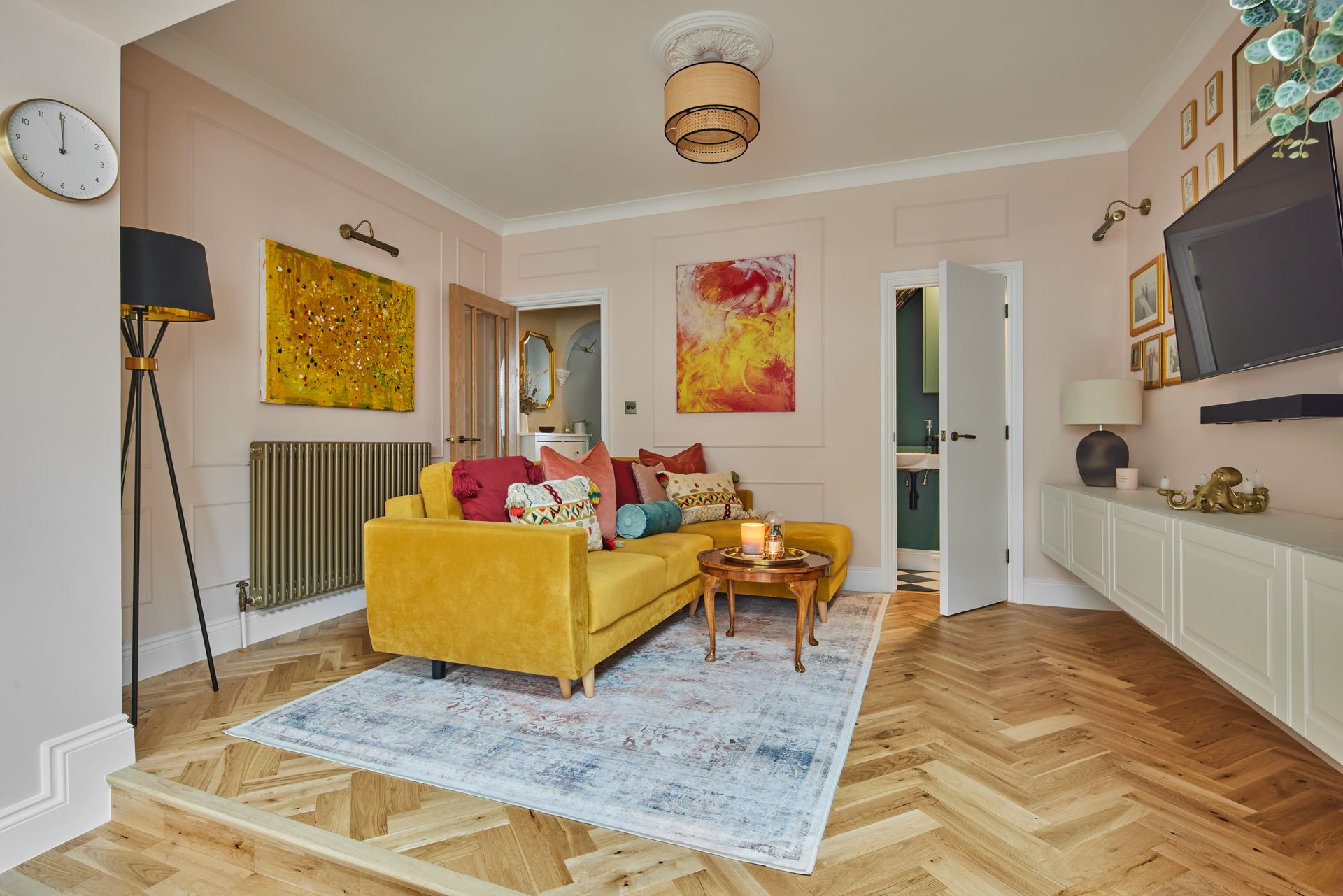 A living room with a yellow couch , table , rug and television.