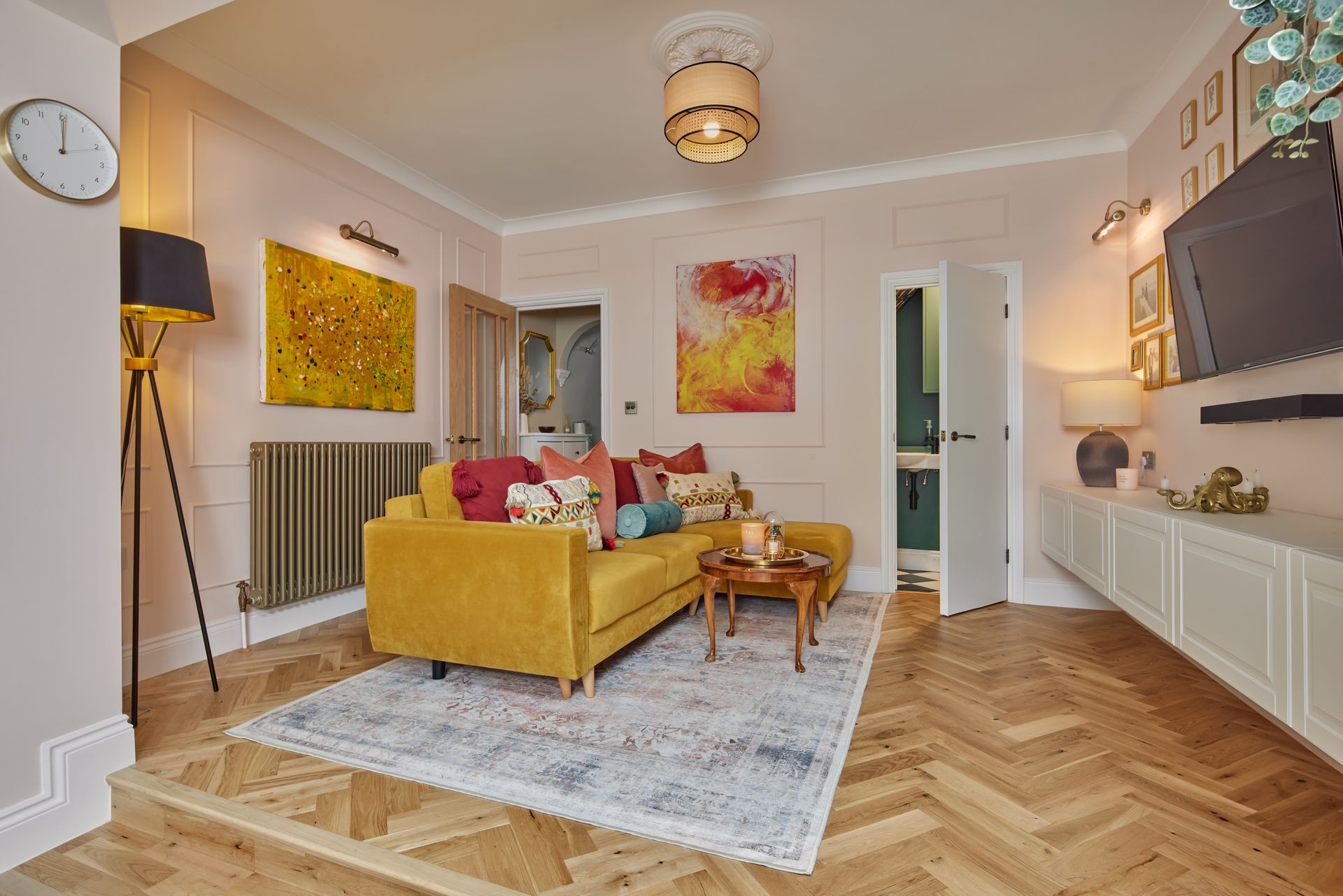 A living room with a yellow couch , a table , and a rug.