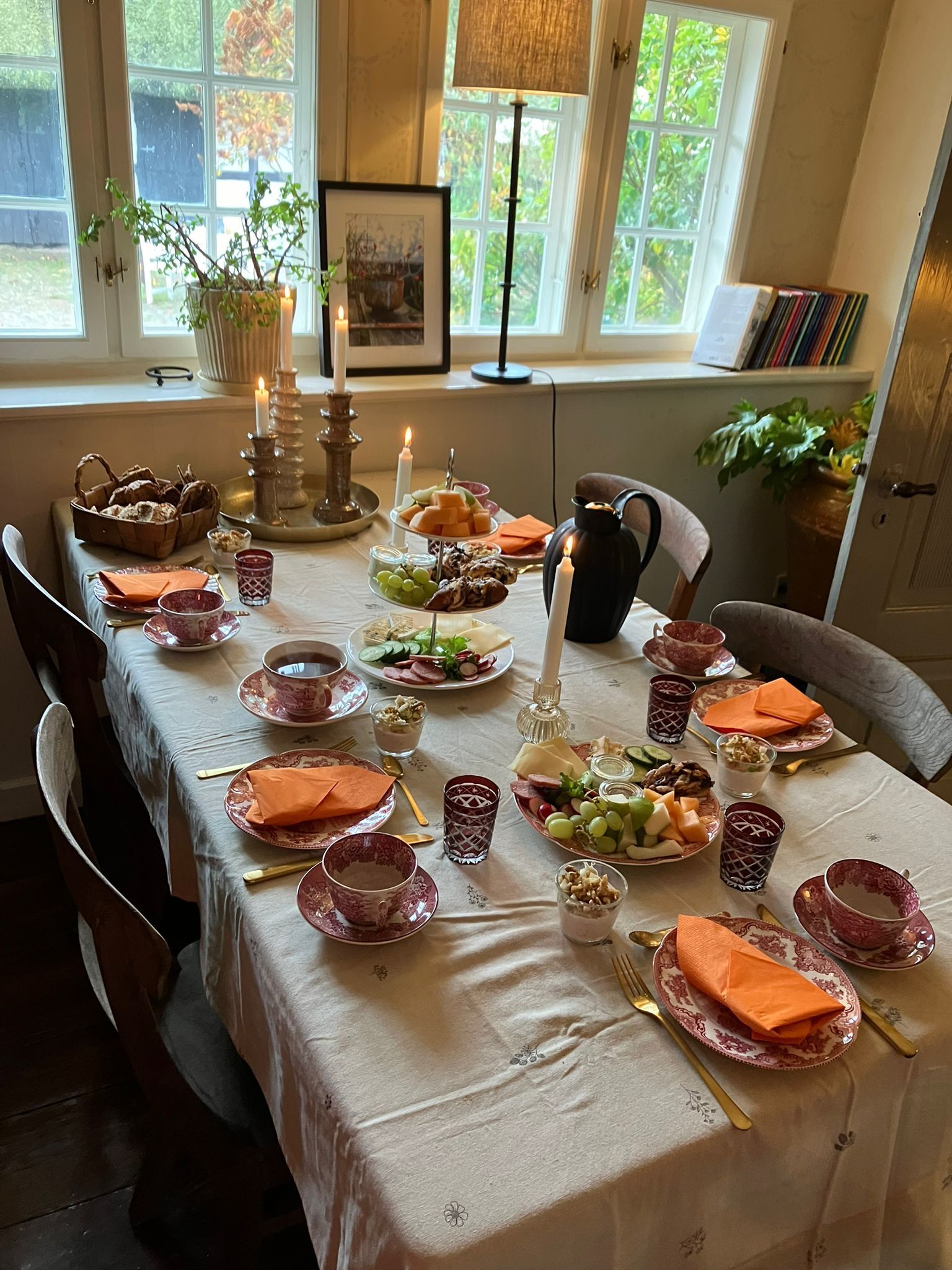 A dining room table with plates , cups , candles and napkins on it.