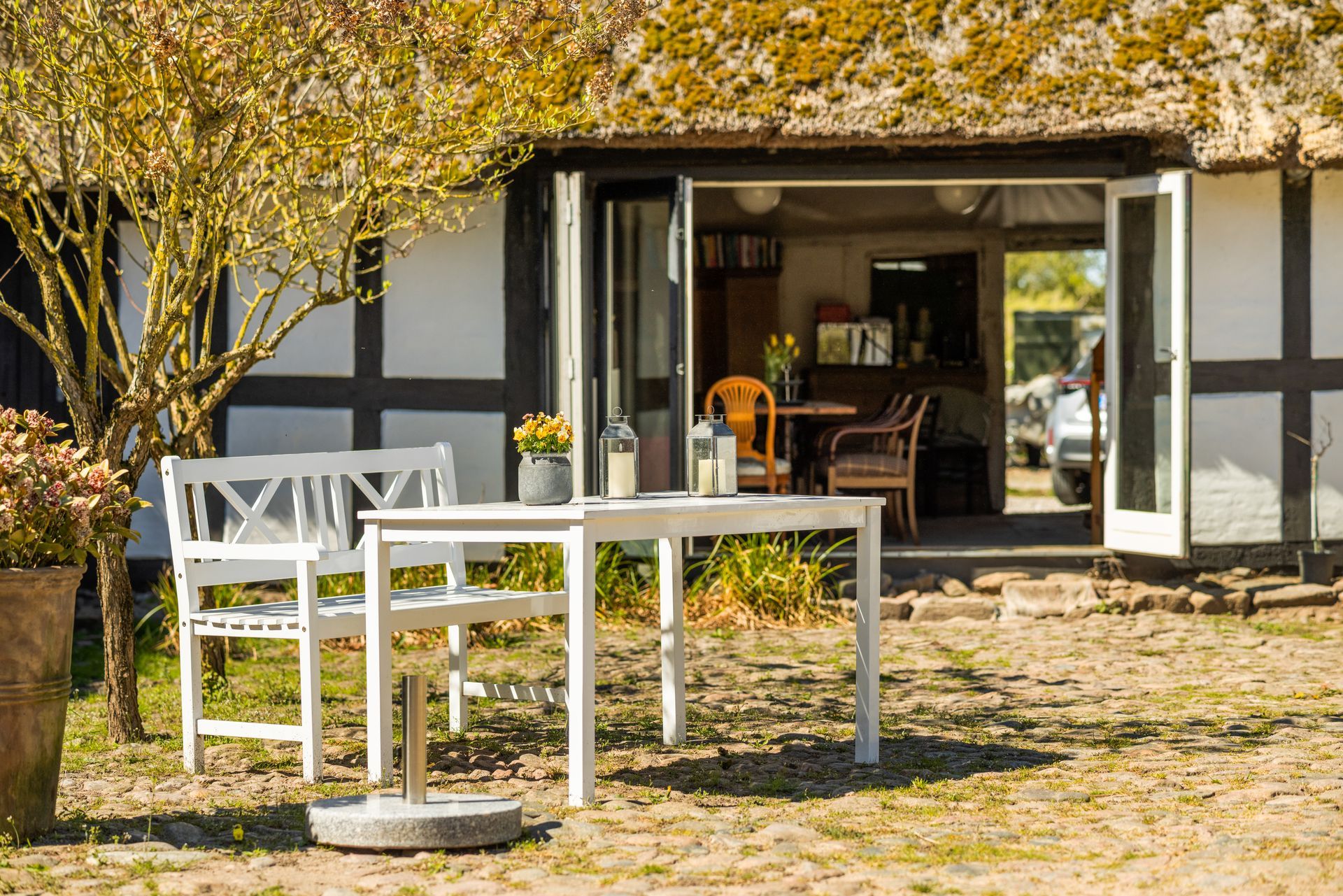 A table and chairs are sitting outside of a thatched roofed house.