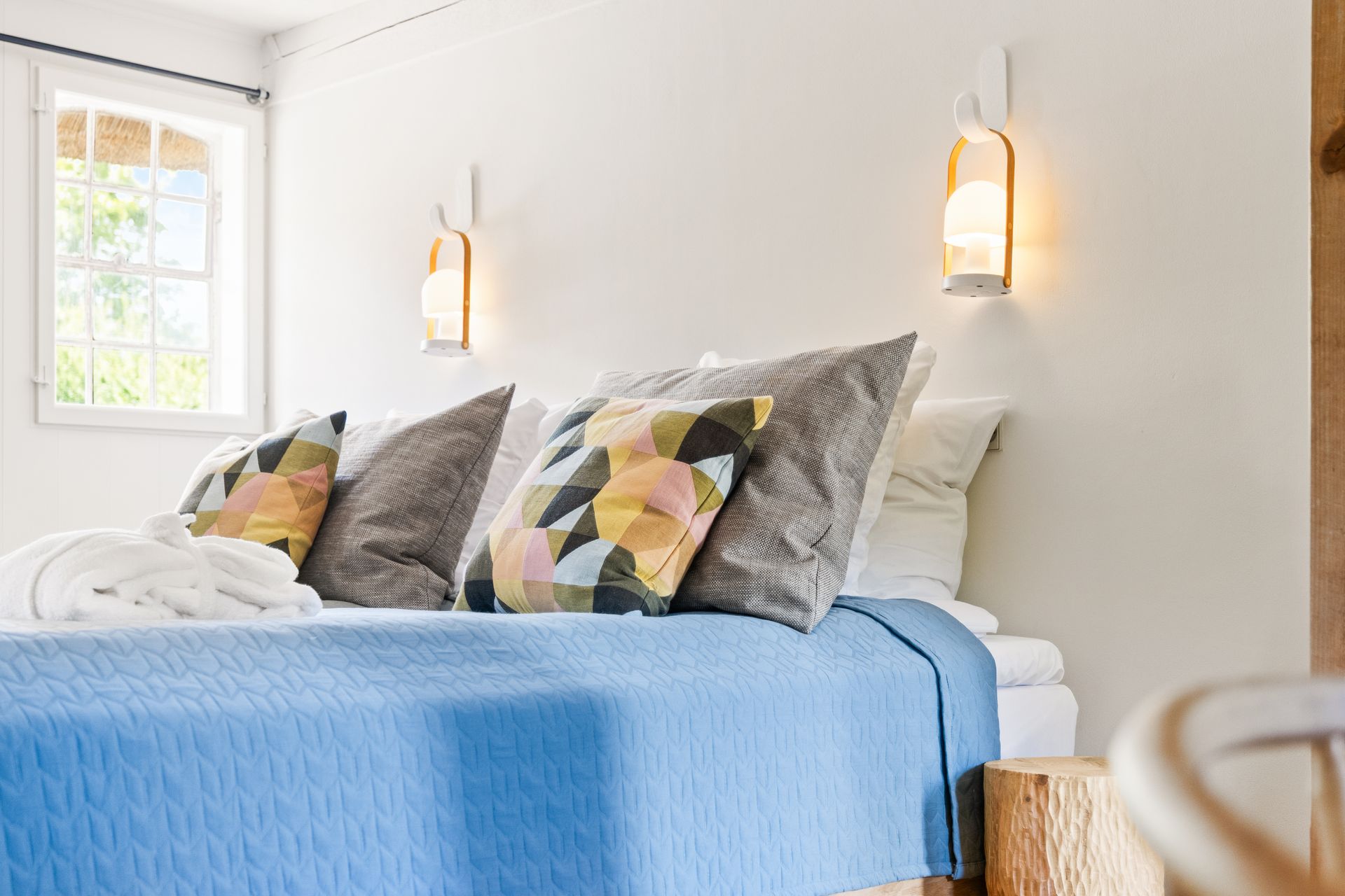 A bedroom with a large bed , dresser , bench , and television.