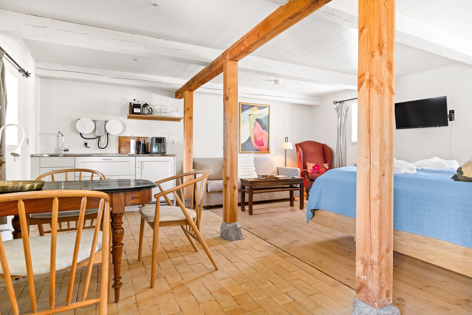 A lovely living room with a table, chairs , kitchen, living area and a comfortable bed.