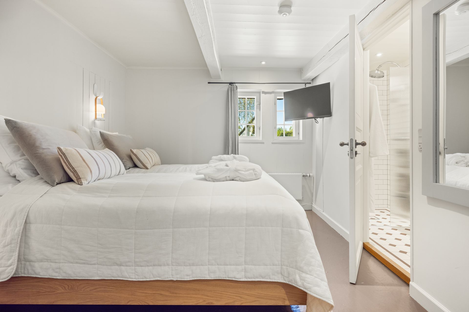 A bedroom with two beds and a television on the wall.