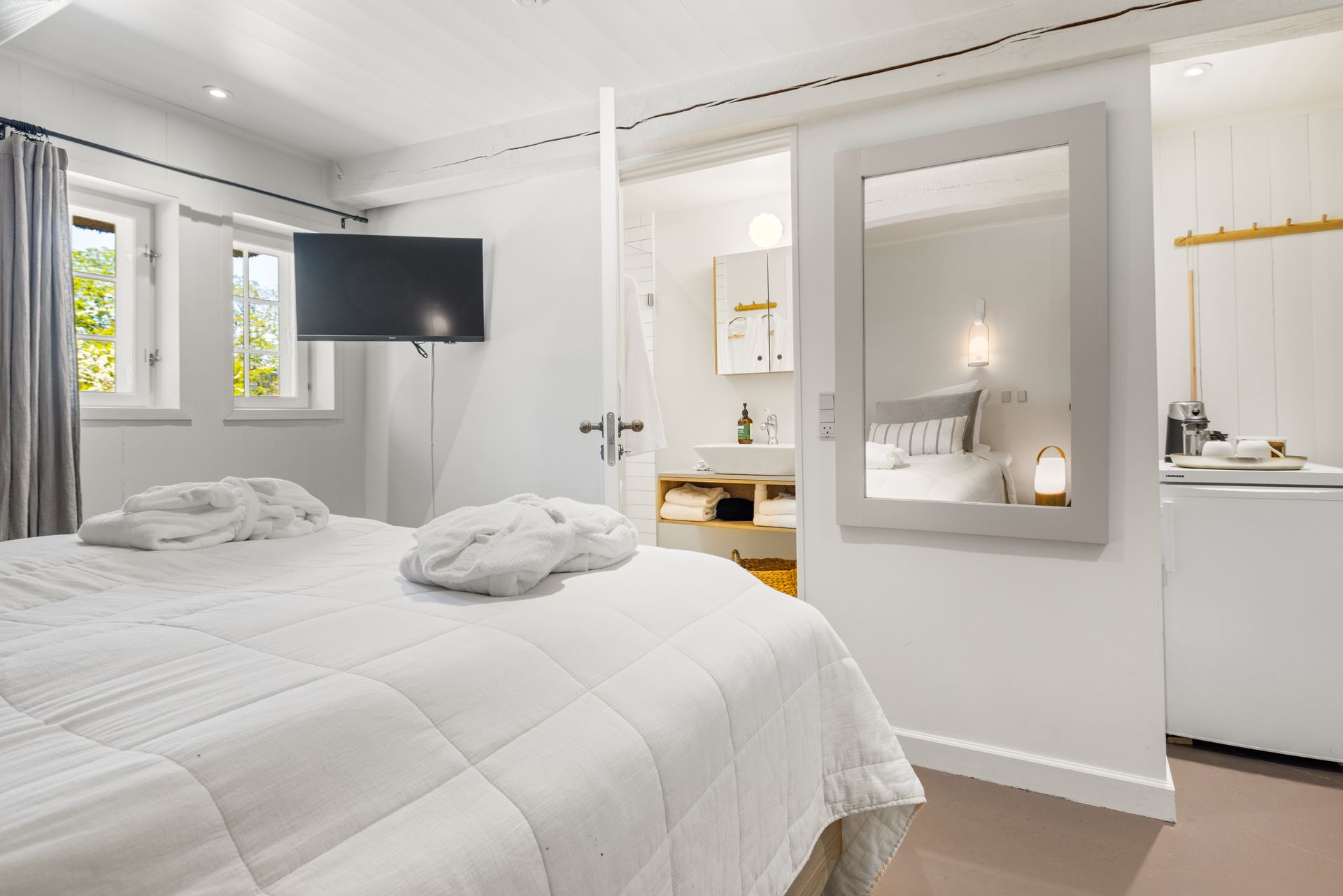 A bedroom with a bed , television , and mirror.
