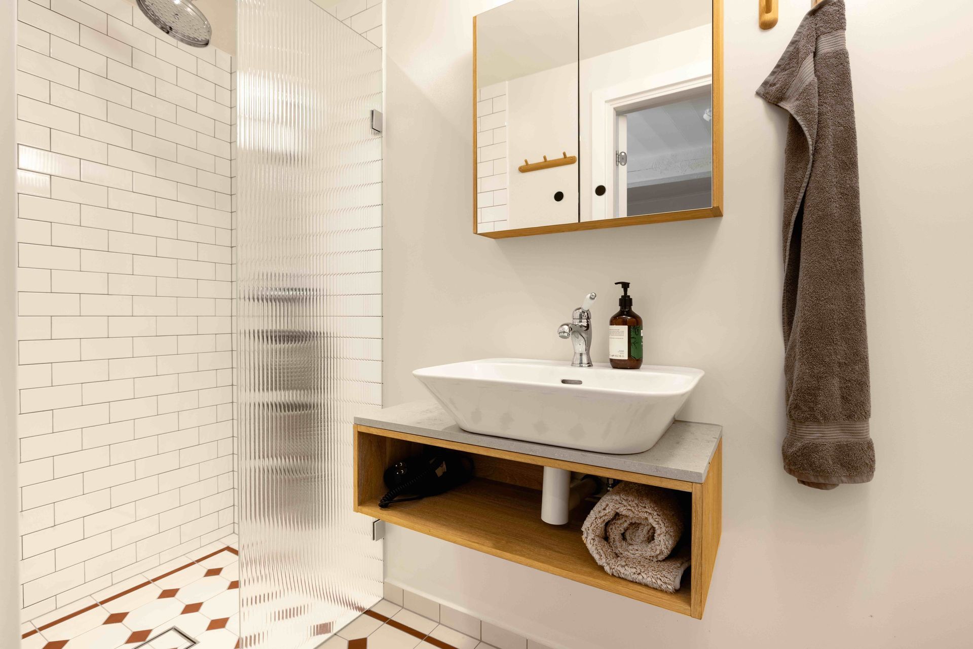 A bathroom with a sink , mirror and walk in shower.