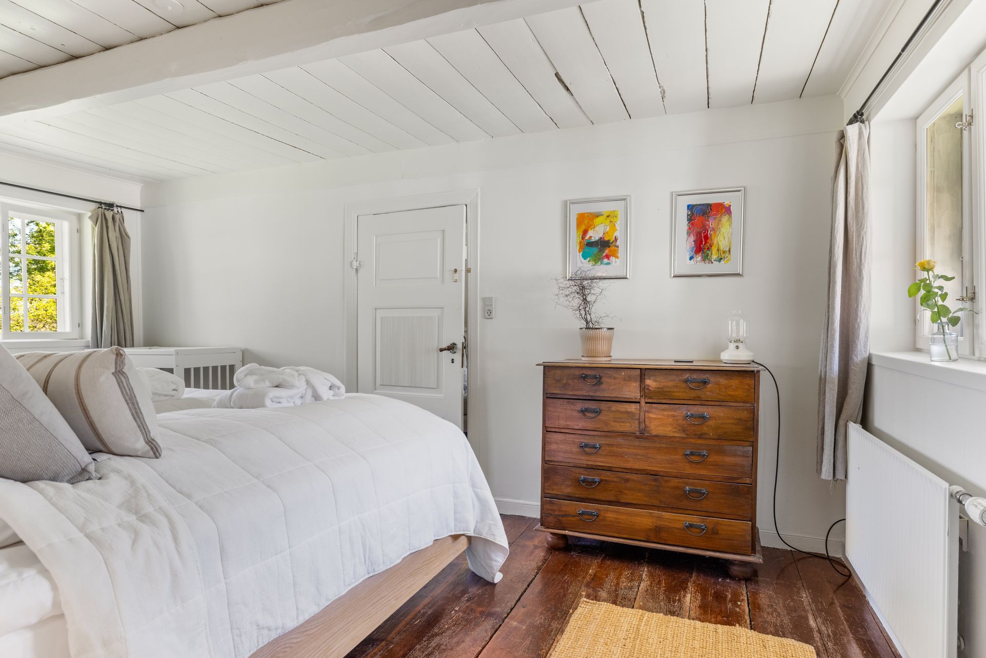 A bedroom with a bed , dresser , and window.