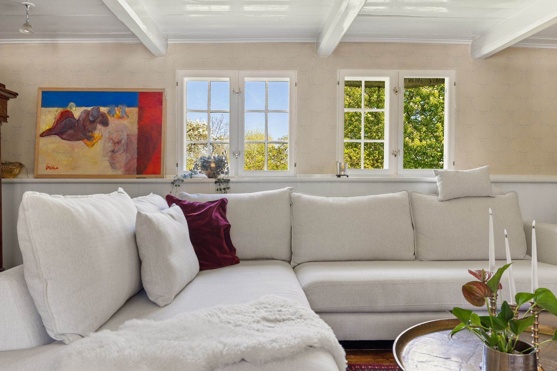 A living room with a white sectional couch and a painting on the wall