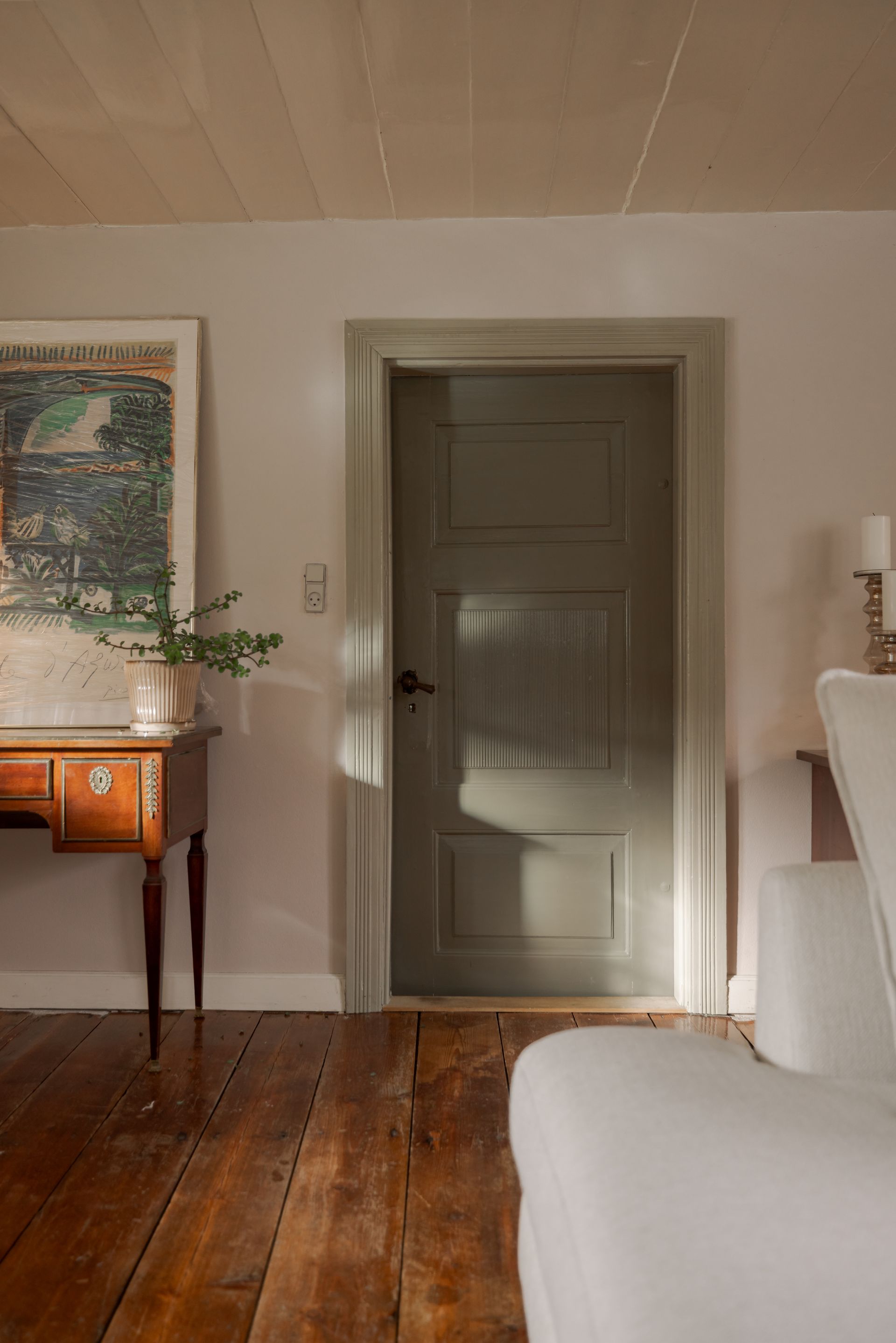 A living room with a chair , desk , and door.