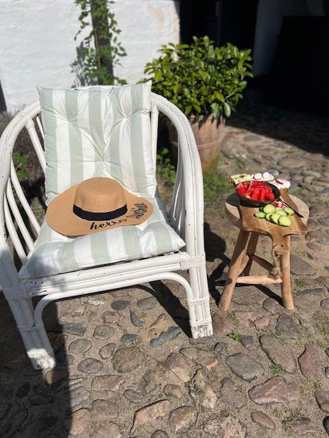 A white wicker chair with a striped cushion and a hat on it.