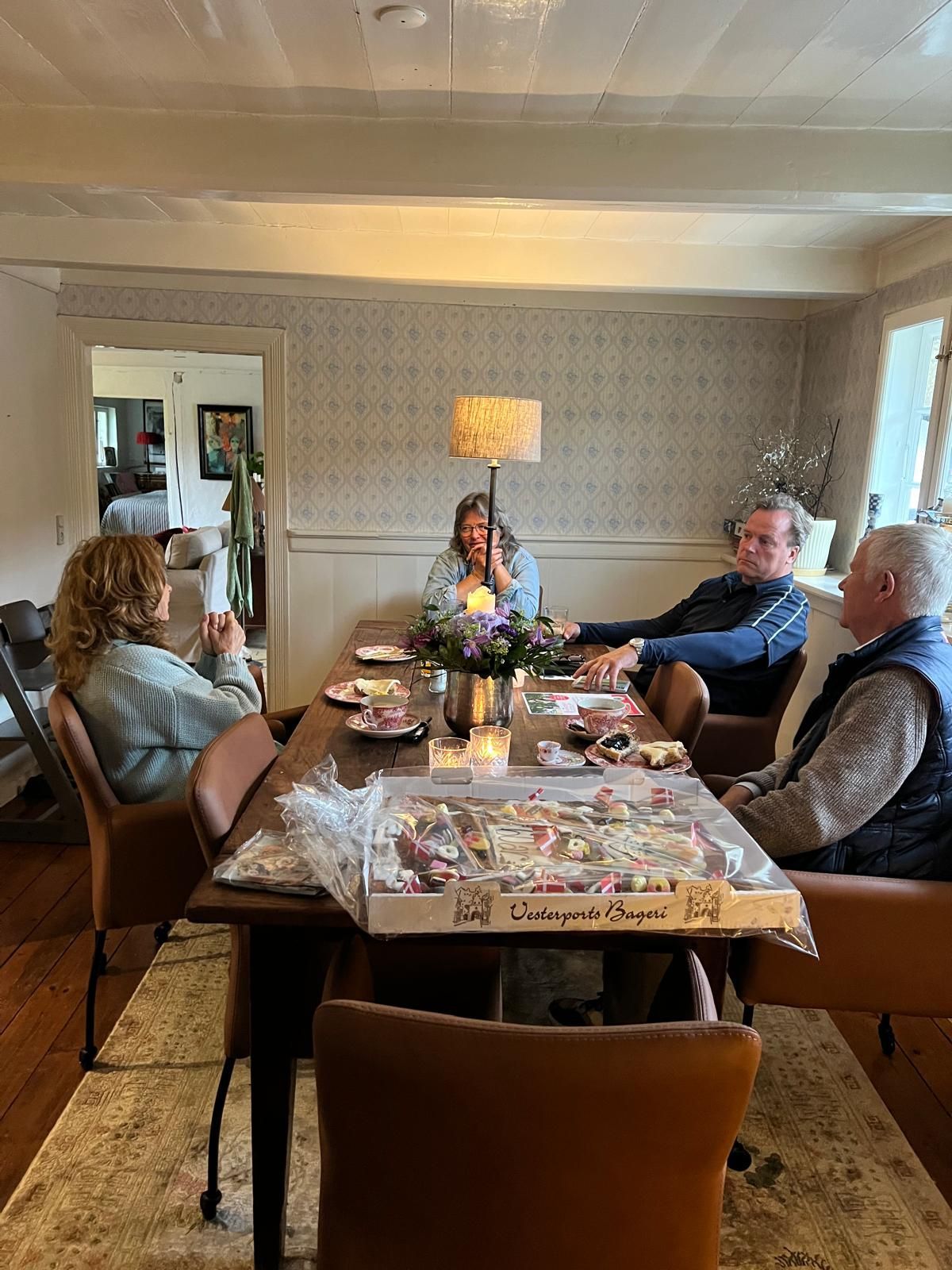A group of people are sitting around a table in a living room.