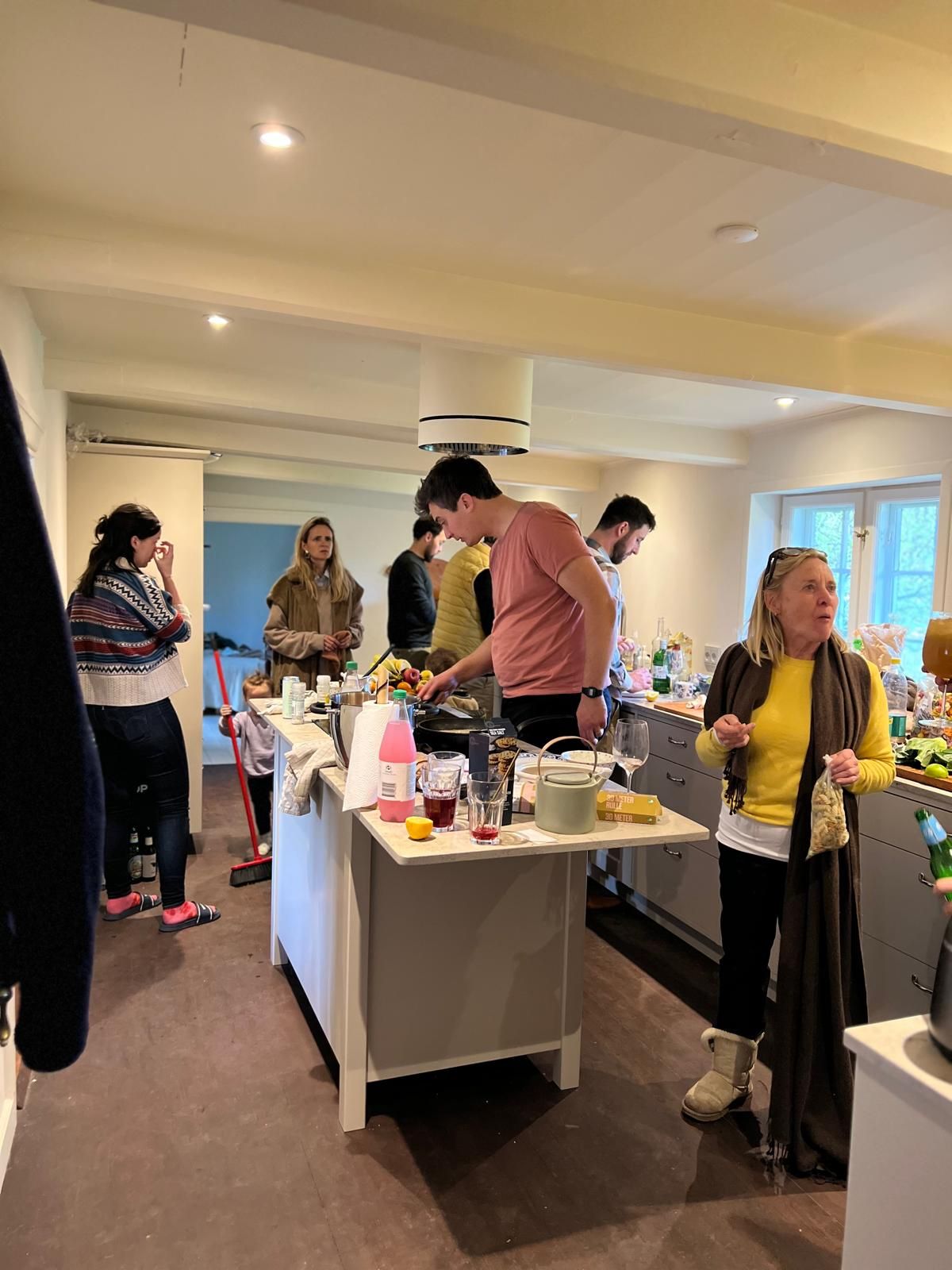 A group of people are standing around a table in a kitchen.