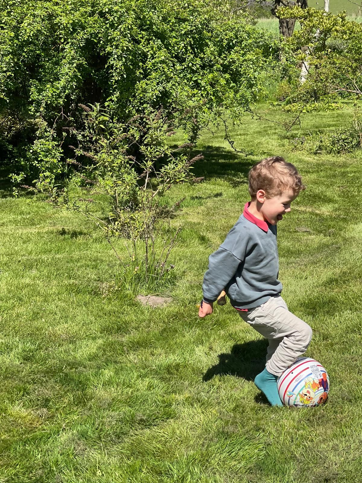 A young boy is kicking a soccer ball in the grass.
