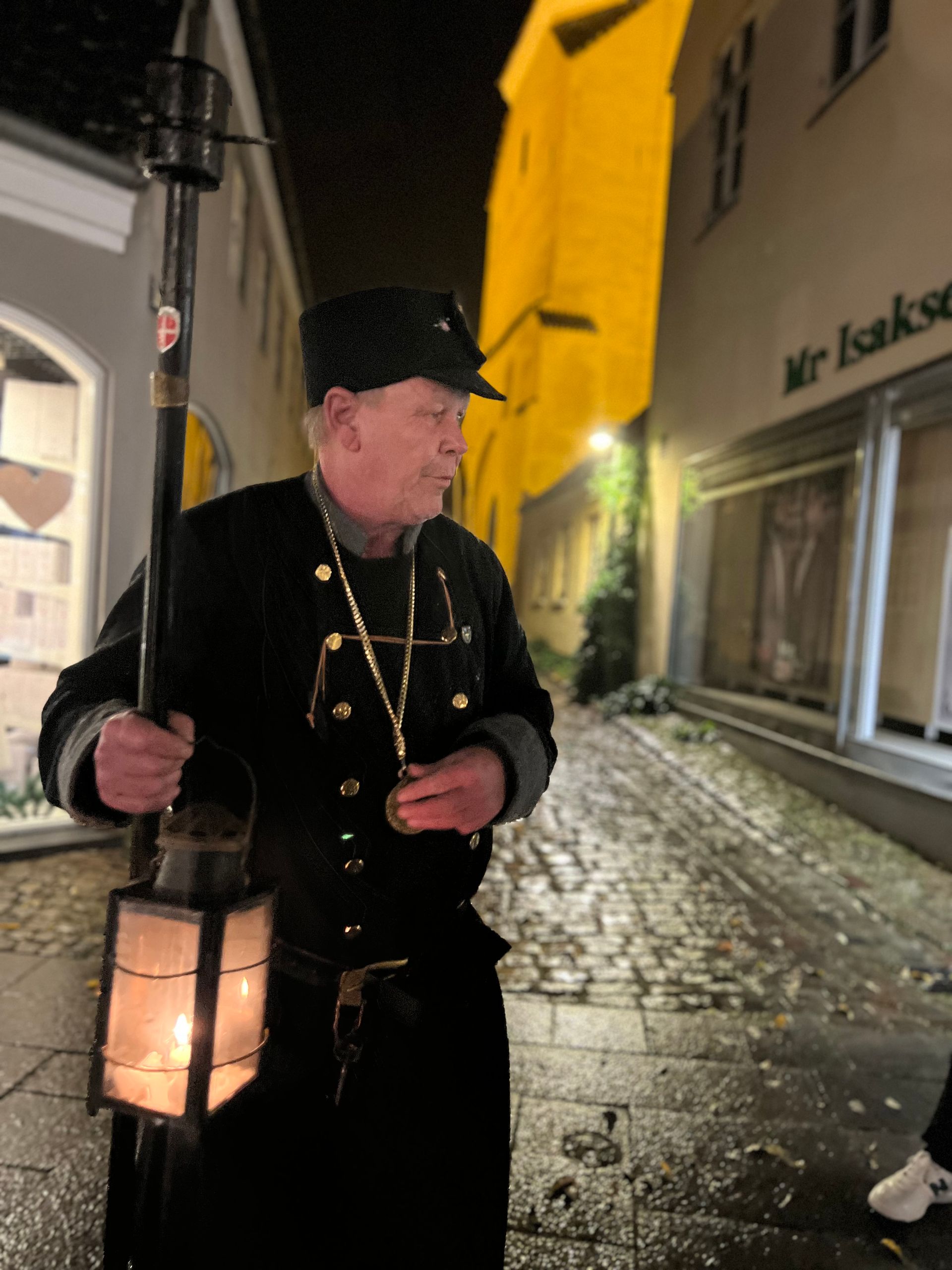 A man is holding a lantern in a dark alleyway