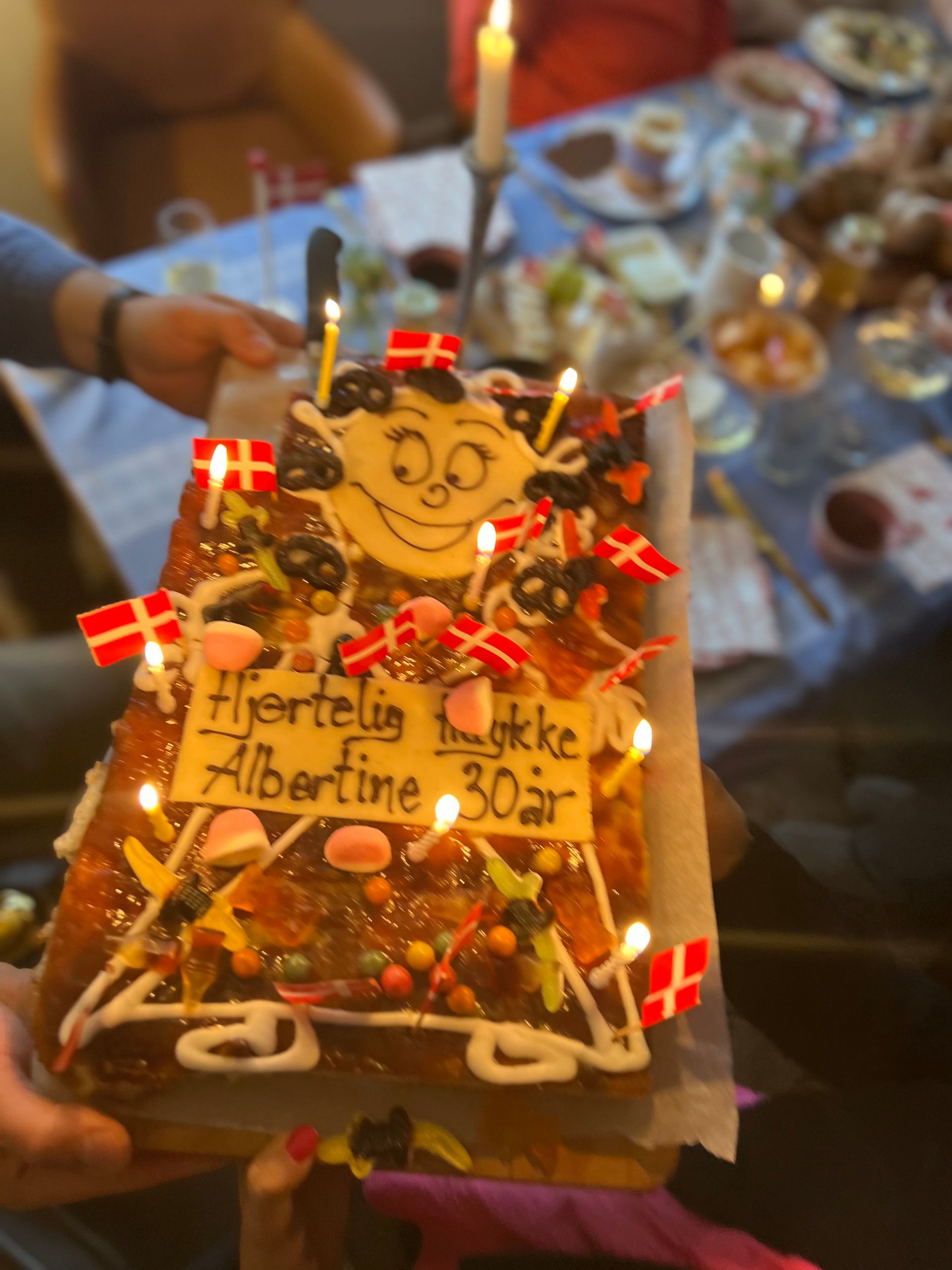 A person is holding a cake that says albertine 30 on it