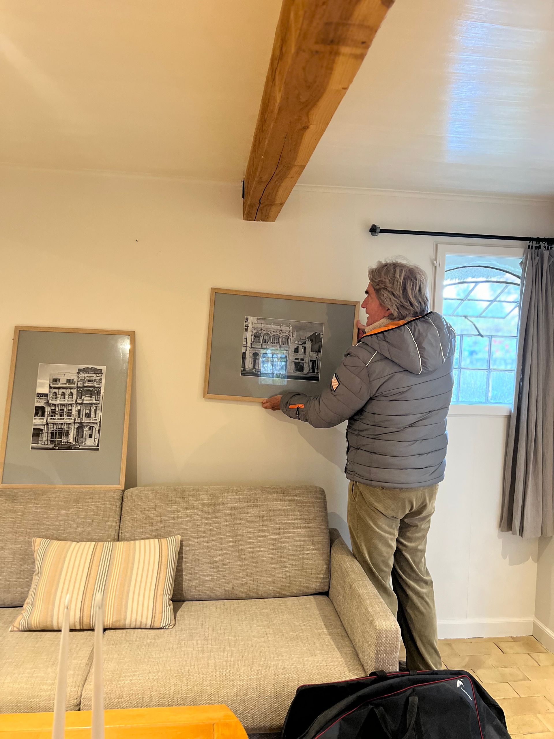 A man is hanging a picture on a wall in a living room.