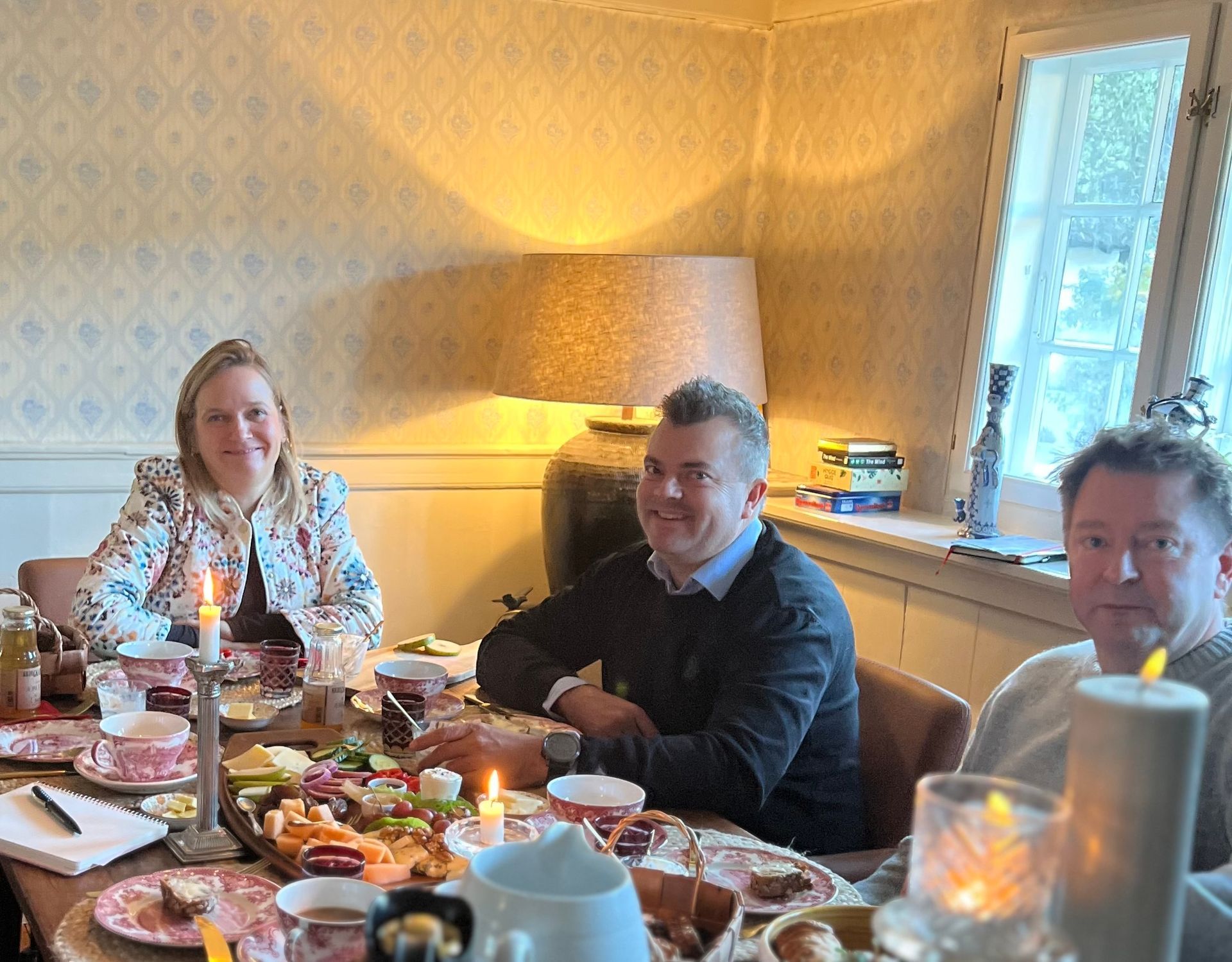 A group of people are sitting at a table with food and candles.
