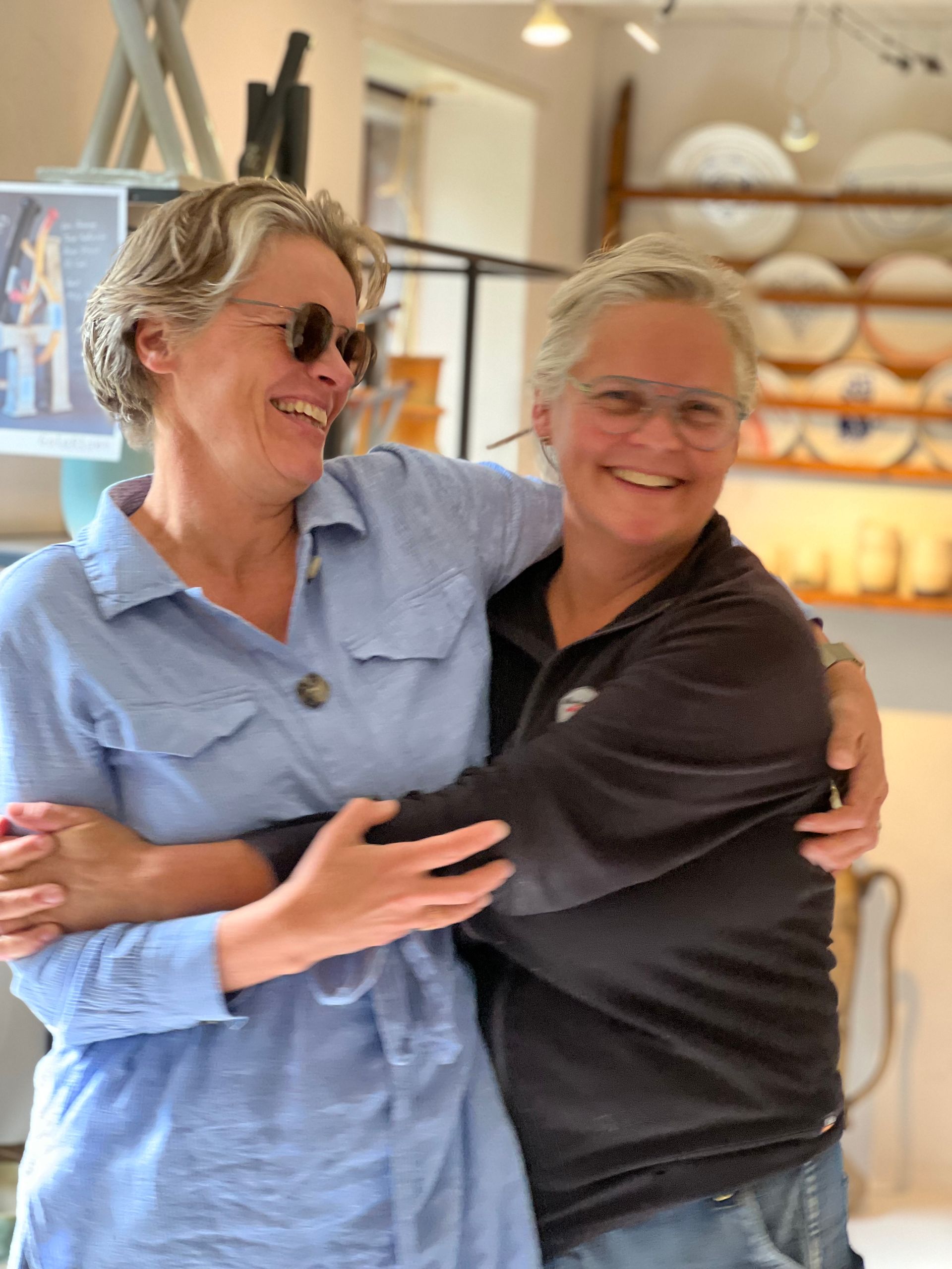 Two women are hugging each other and smiling in a kitchen.