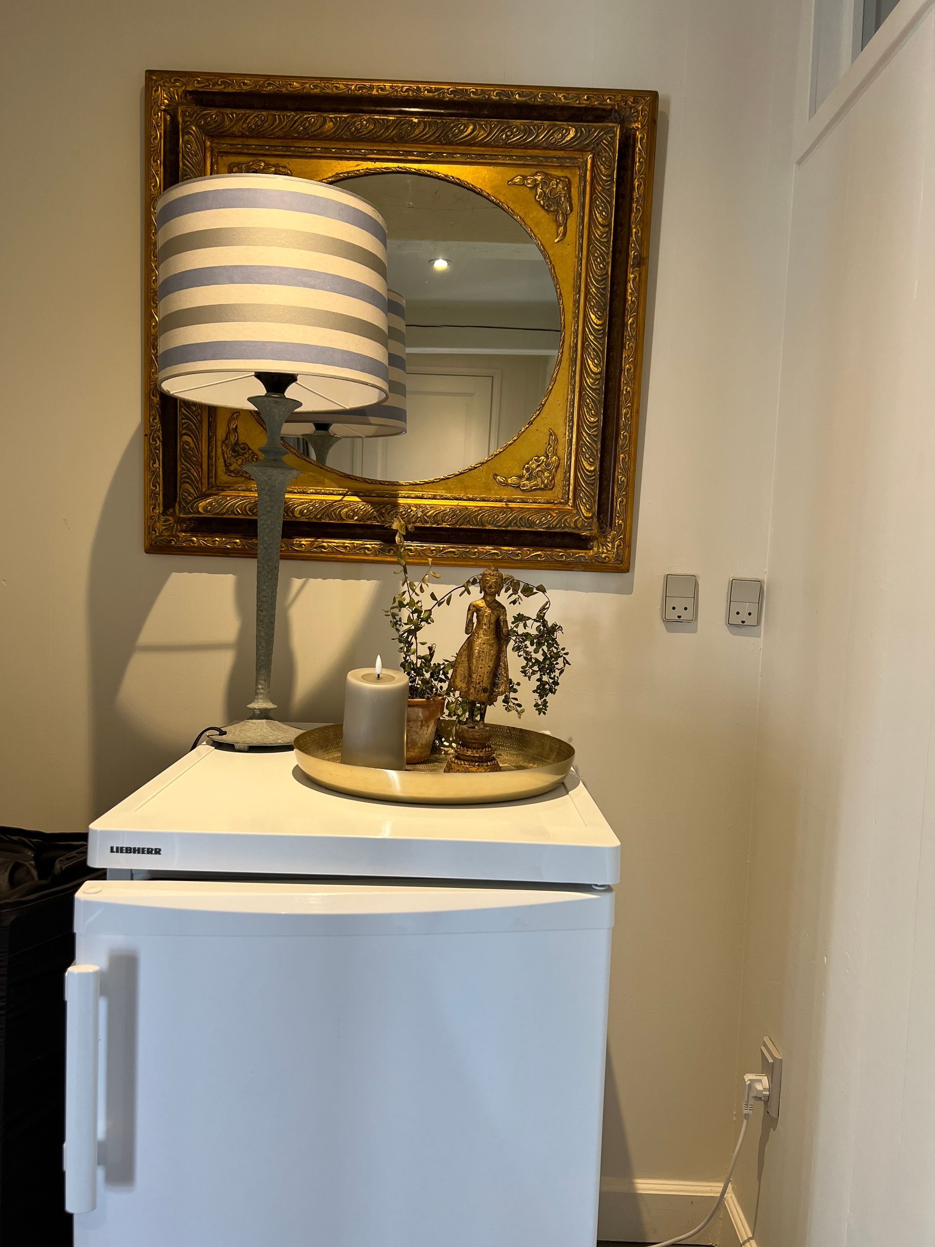 A lamp is sitting on top of a white table next to a mirror.